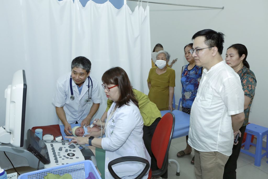 Các bác sĩ đang tiến hành siêu âm cho em bé sơ sinh để sàng lọc bệnh